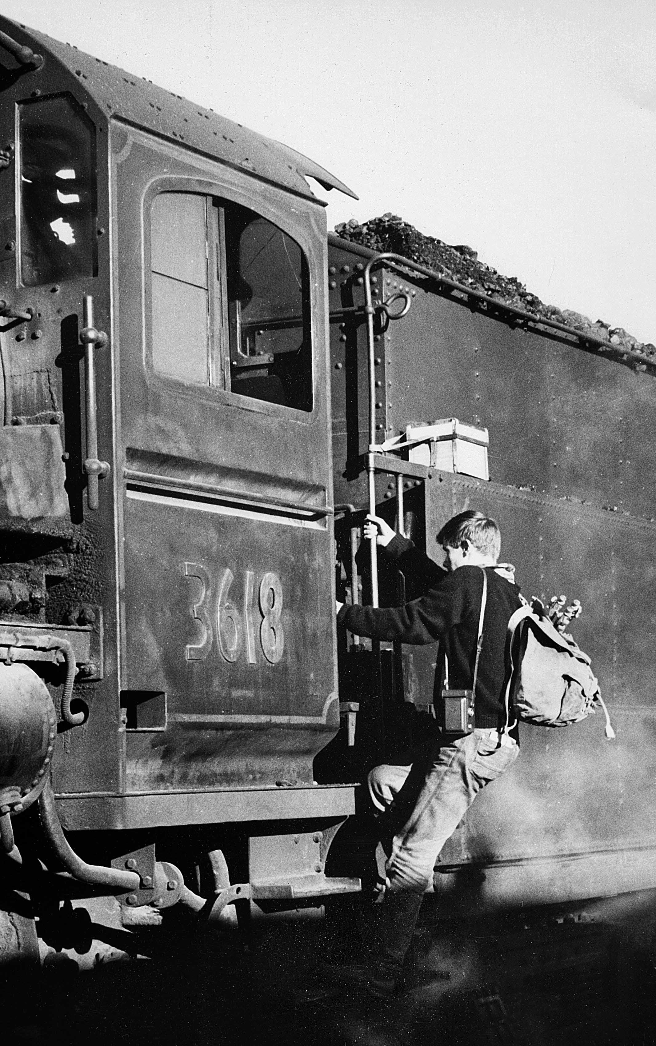 A young Graham Palmer climbing aboard locomotive 3618 with a camera and backpack, Orange NSW, 1967.